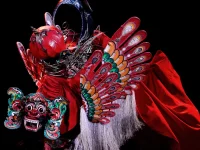 Barong Kemiren bersayap dan bermahkota merah dalam sebuah pertunjukan di panggung gelap