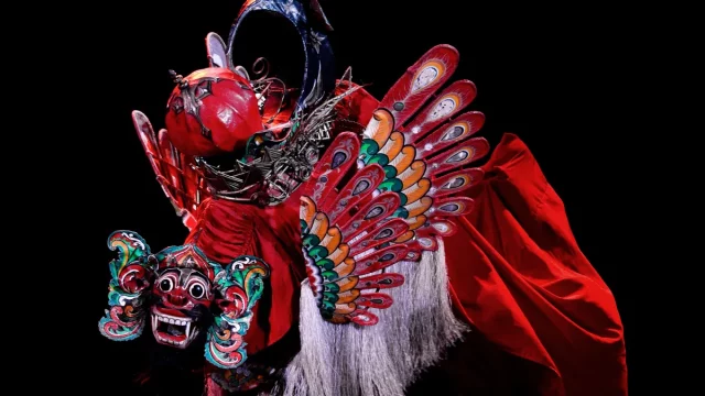 Barong Kemiren bersayap dan bermahkota merah dalam sebuah pertunjukan di panggung gelap