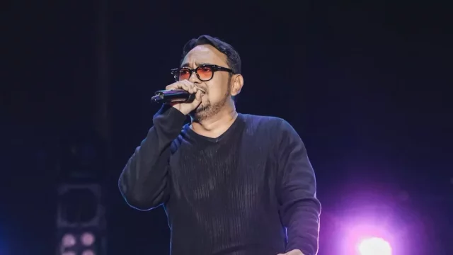 Bebi Romeo menyanyi di atas panggung sambil menggenggam mikrofon.