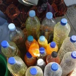 Sekeranjang botol plastik berisi jamu berwarna kuning, jingga, dan cokelat