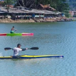 Dua atlet dayung mengayuh perahu kayak di perairan tenang