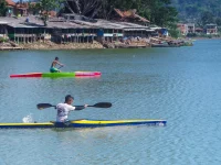 Dua atlet dayung mengayuh perahu kayak di perairan tenang