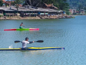 Dua atlet dayung mengayuh perahu kayak di perairan tenang