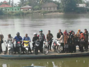 Perahu ketek penuh penumpang dan sepeda motor menyeberangi Sungai Komering.