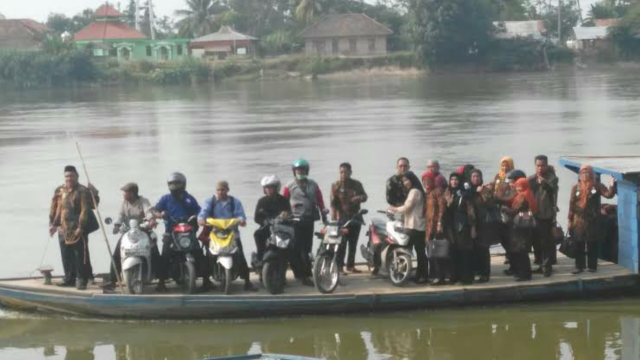 Perahu ketek penuh penumpang dan sepeda motor menyeberangi Sungai Komering.