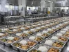 Deretan ompreng berisi nasi dan lauk di meja baja dapur makan bergizi gratis