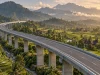 Jalan tol layang membentang di atas lembah persawahan dan rumah gonjong Sumatera Barat