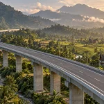 Jalan tol layang membentang di atas lembah persawahan dan rumah gonjong Sumatera Barat