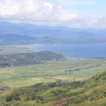 Hamparan sawah, permukiman, dan Danau Kerinci dilihat dari lereng Bukit Kayangan