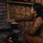 Perempuan memasak dengan tungku kayu di sebuah dapur tradisional