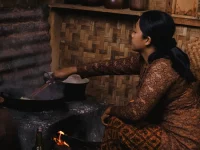 Perempuan memasak dengan tungku kayu di sebuah dapur tradisional