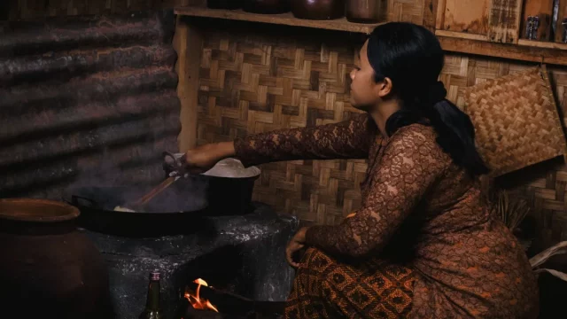 Perempuan memasak dengan tungku kayu di sebuah dapur tradisional