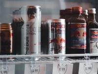 Kaleng dan botol minuman energi berjajar di rak lemari pendingin toko berlabel harga