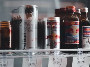 Kaleng dan botol minuman energi berjajar di rak lemari pendingin toko berlabel harga