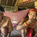 Dua sikerei Mentawai lanjut usia bertato duduk di lantai rumah uma