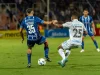 Dua pemain sepak bola berebut bola di lapangan berumput hijau