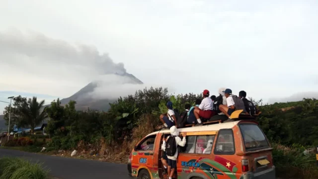 Warga menyaksikan erupsi Gunung Sinabung dari atas angkutan umum di Kabupaten Karo, Sumatera Utara