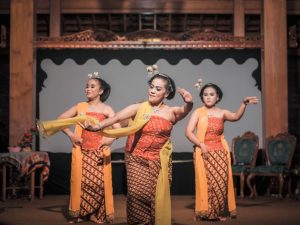 Ilustrasi tiga penari perempuan berkebaya membawakan tari tradisional di atas panggung.