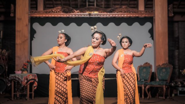 Ilustrasi tiga penari perempuan berkebaya membawakan tari tradisional di atas panggung.