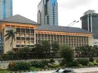 Gedung Bank Indonesia beratap limas di tepi jalan dengan gedung tinggi di belakangnya