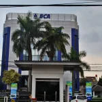 Gedung kantor Bank Central Asia empat lantai dengan pohon palem di halaman depan