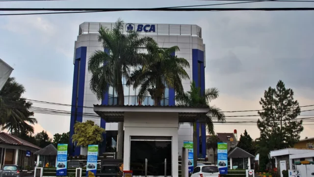 Gedung kantor Bank Central Asia empat lantai dengan pohon palem di halaman depan
