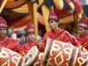 Pemain gandang Minangkabau berbaju merah dan bertopi tinggi menabuh gendang bermotif