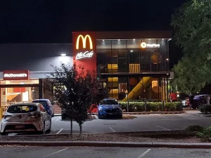 Gerai McDonald's dengan papan McCafe menyala pada malam hari di Karawara, Perth, Australia