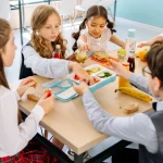 Sekelompok anak duduk semeja menyantap makanan di kantin sekolah