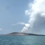 Ilustrasi erupsi gunung api di tengah laut dengan kolom asap mengepul