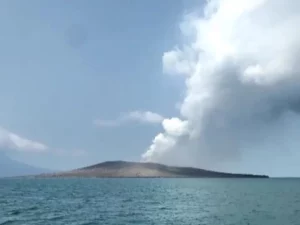 Ilustrasi erupsi gunung api di tengah laut dengan kolom asap mengepul