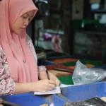 Ilustrasi pedagang pasar mencatat penjualan harian di kiosnya