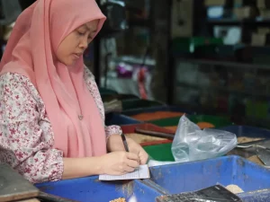 Ilustrasi pedagang pasar mencatat penjualan harian di kiosnya