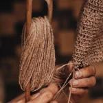 Perajin menganyam serat alami secara tradisional dengan kedua tangan