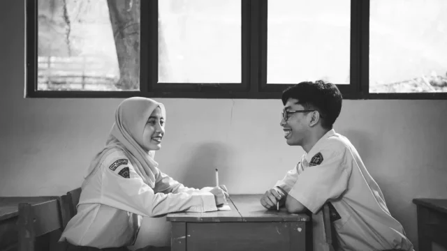 Ilustrasi dua pelajar berbincang di ruang kelas