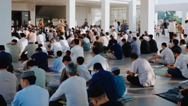 Ilustrasi jemaah laki-laki duduk berbaris di dalam ruang masjid