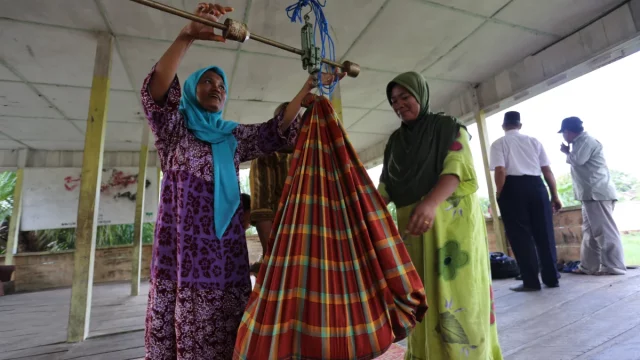 Dua kader posyandu menimbang bayi dengan timbangan dacin berkain gendong