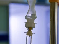 Tabung tetes infus bening menggantung di samping tiang infus di ruang rawat rumah sakit