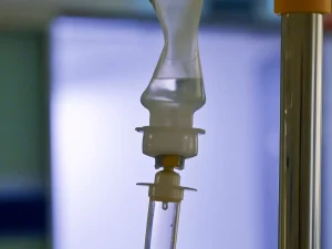 Tabung tetes infus bening menggantung di samping tiang infus di ruang rawat rumah sakit