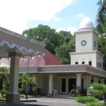 Gedung Balai Kota Mataram bermenara jam putih dengan pohon palem di halaman