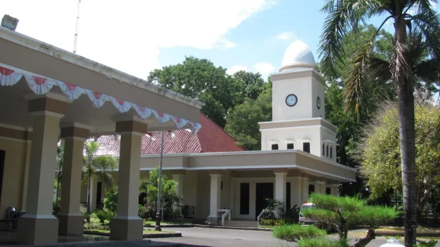 Gedung Balai Kota Mataram bermenara jam putih dengan pohon palem di halaman