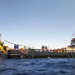 Kapal penunjang lepas pantai dengan derek kuning di tengah laut