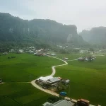 Pemandangan udara bukit-bukit karst, sawah, dan permukiman di kawasan Rammang-Rammang