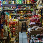 Pedagang di kios kelontong dengan aneka barang dagangan