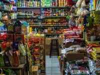 Pedagang di kios kelontong dengan aneka barang dagangan