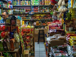Pedagang di kios kelontong dengan aneka barang dagangan