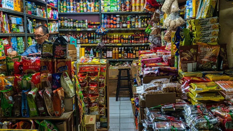 Pedagang di kios kelontong dengan aneka barang dagangan