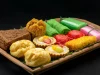 Aneka kue tradisional berwarna-warni tertata di atas nampan kayu berlatar gelap