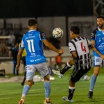 Para pemain sepak bola berduel dalam pertandingan malam di bawah lampu stadion