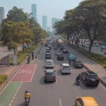 Mobil dan sepeda motor melaju di jalan raya Jakarta berlatar gedung tinggi